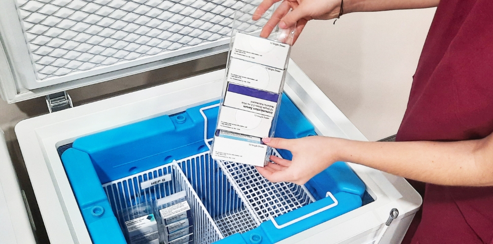 Woman's hands removing supplies from a TempArmour vaccine refrigerator