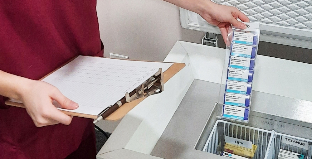 Person with clipboard taking supplies out of a TempArmour vaccine refrigerator