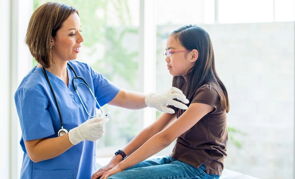 Nurse preparing to administer a vaccine to a girl