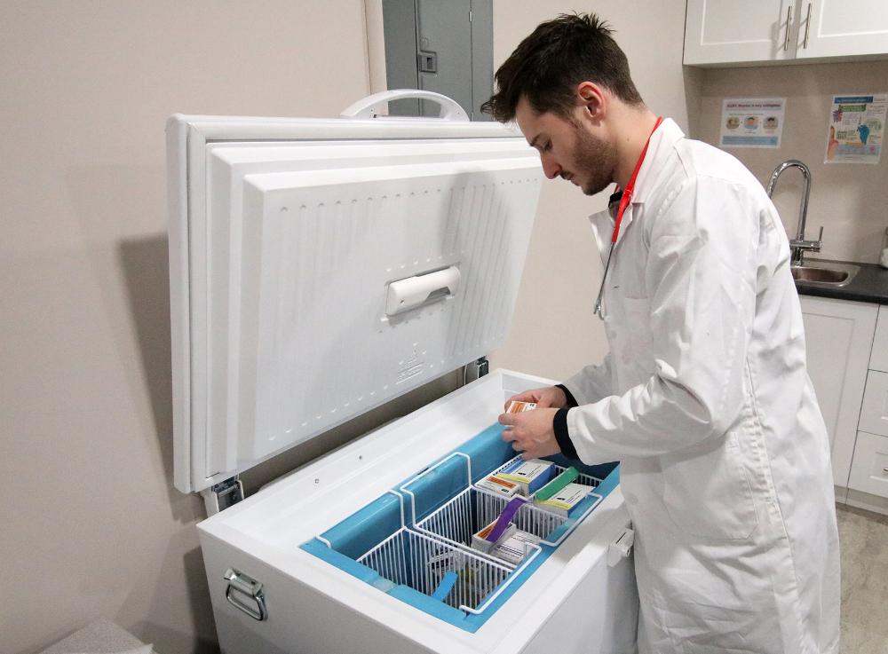 Man in white coat checking supplies in a freezer